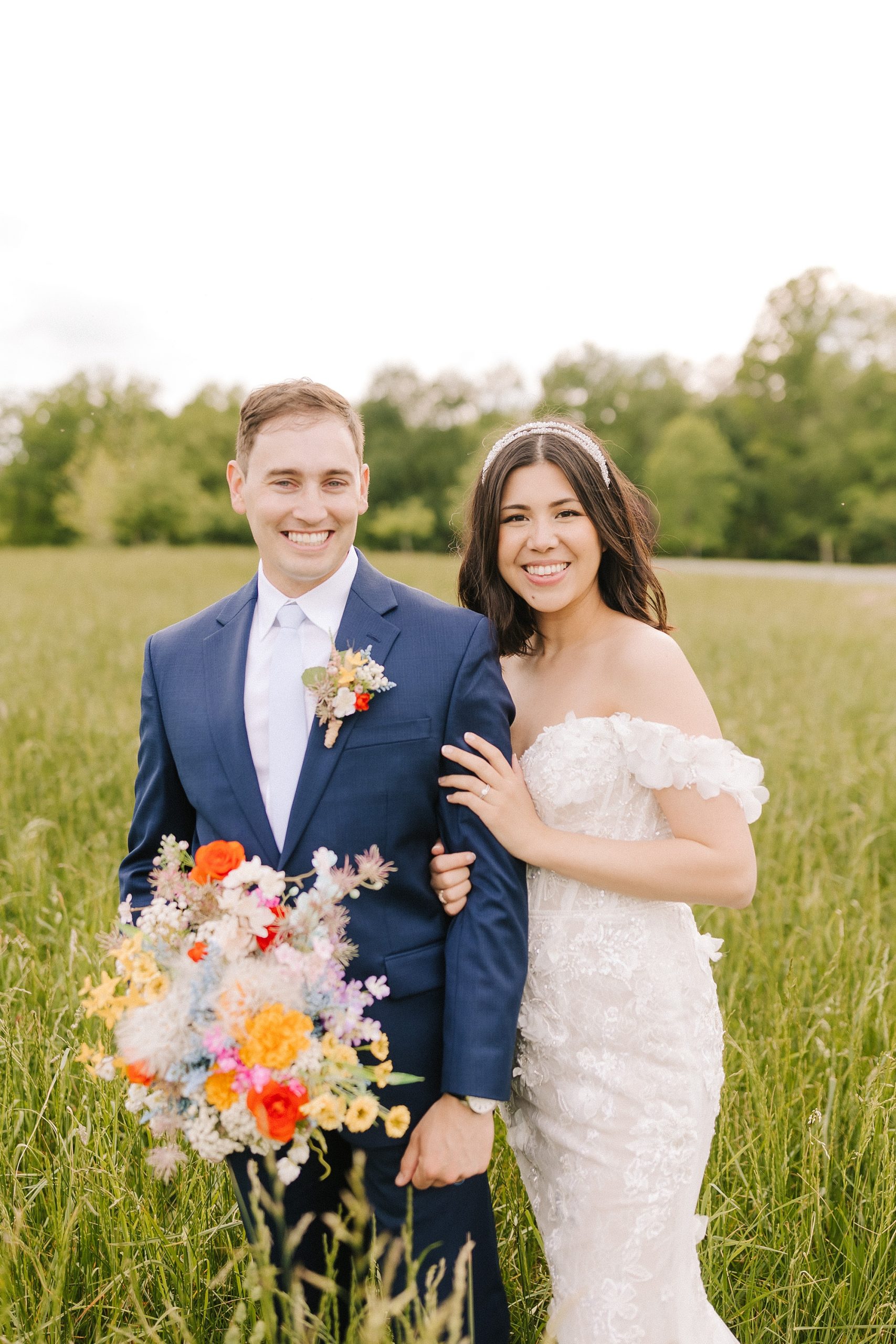 bride and groom stand together with bouquet of wildflowers 