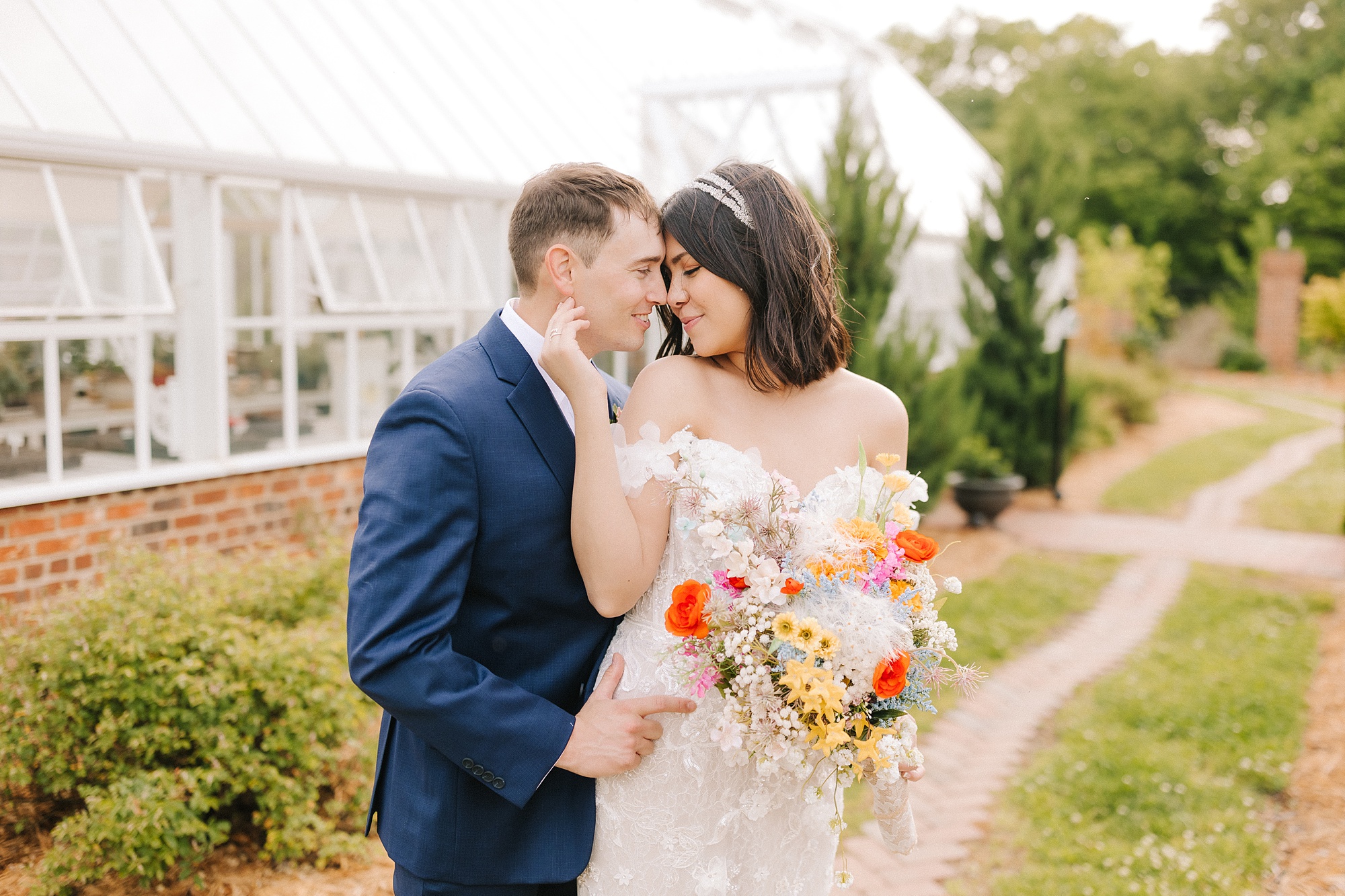bride holds groom's chin during portraits in NC