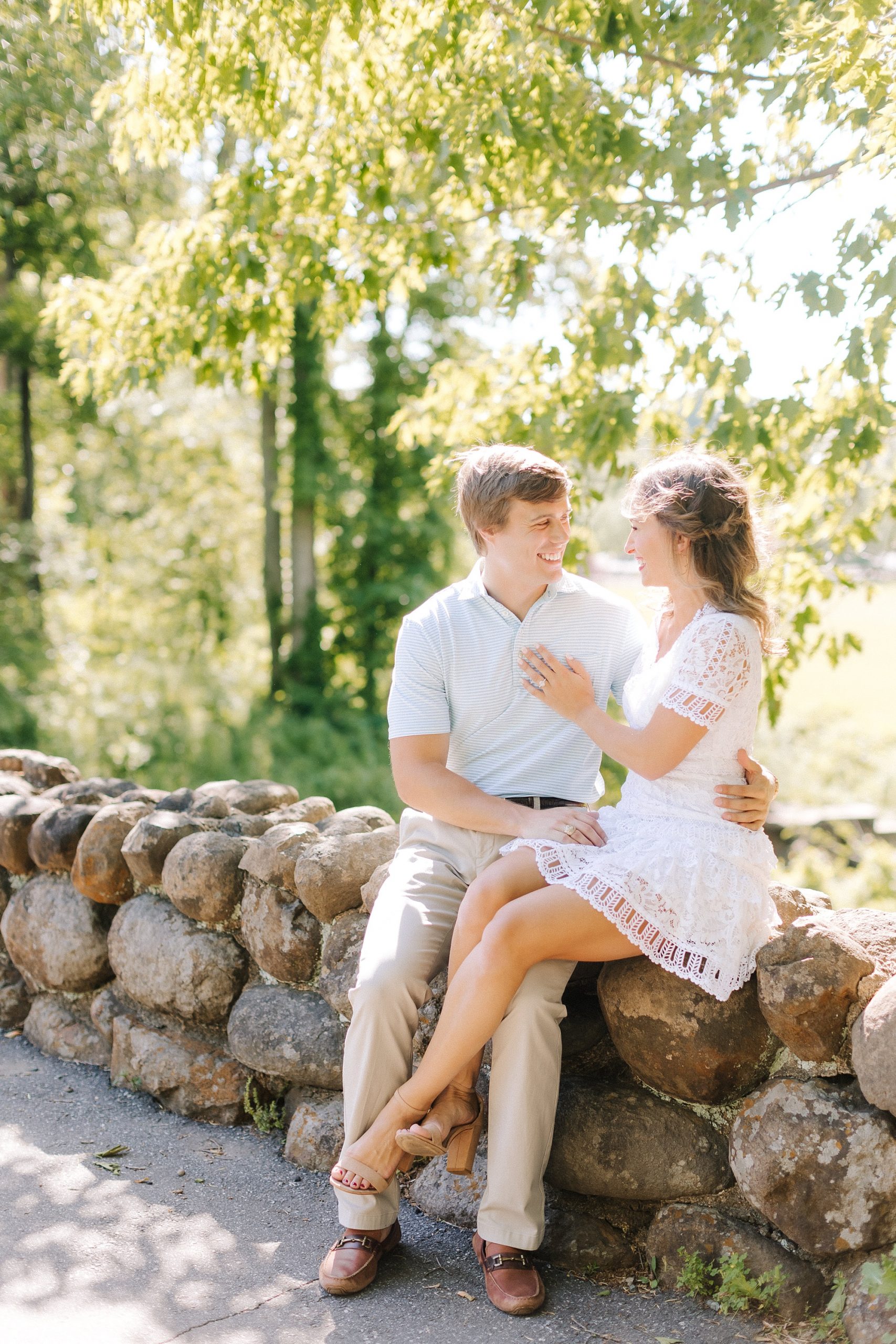 bride and groom sit on rock wall in Reynolda Gardens
