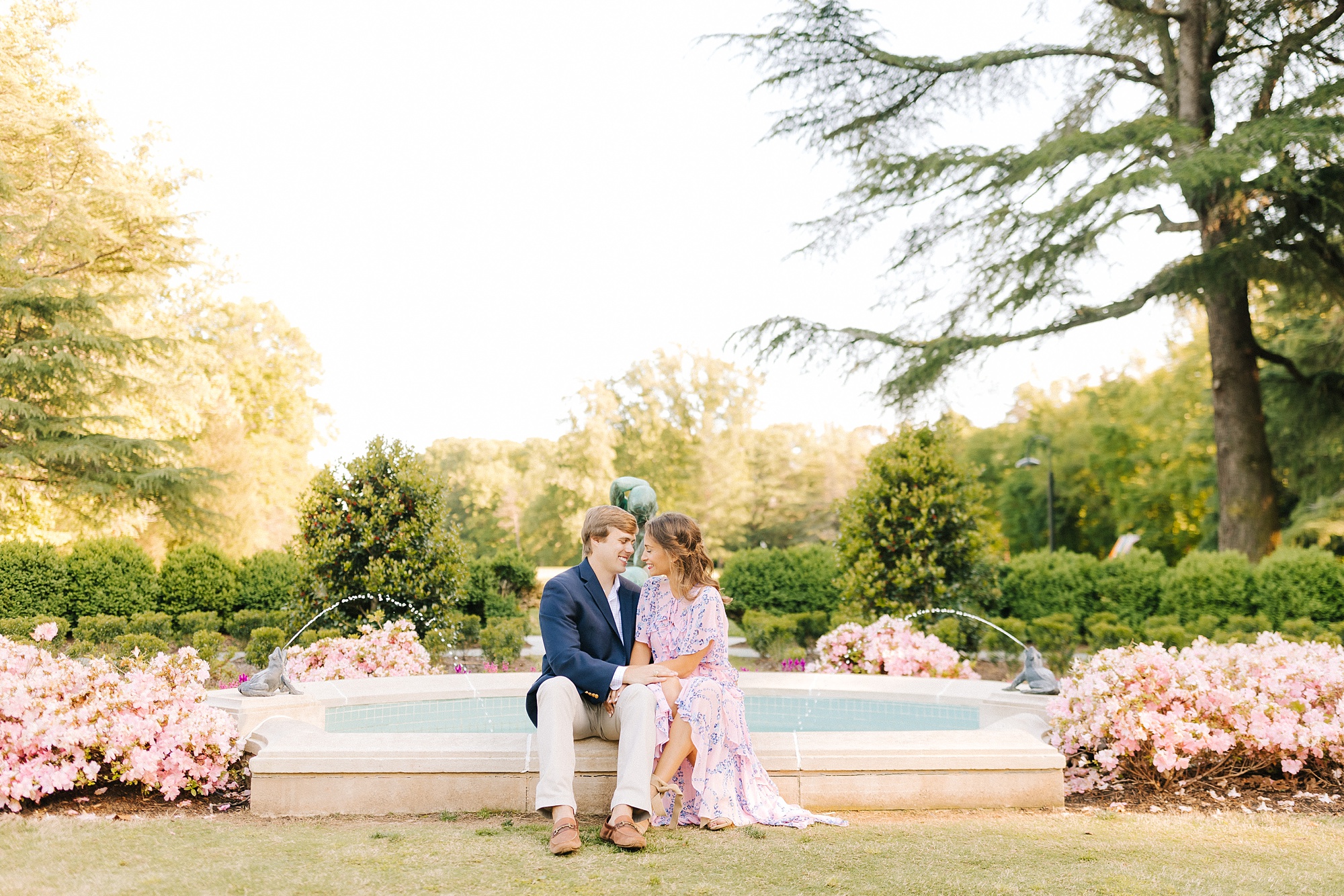 engaged couple sits by fountain in Reynolda Gardens
