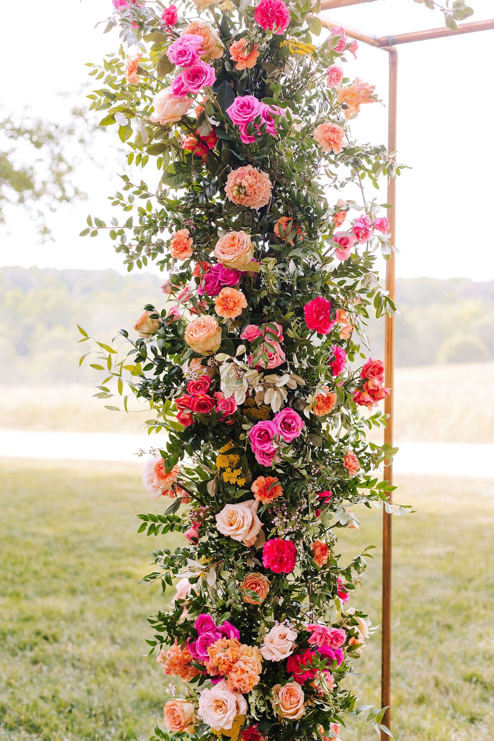 bright pink and orange flowers on arbor for ceremony 