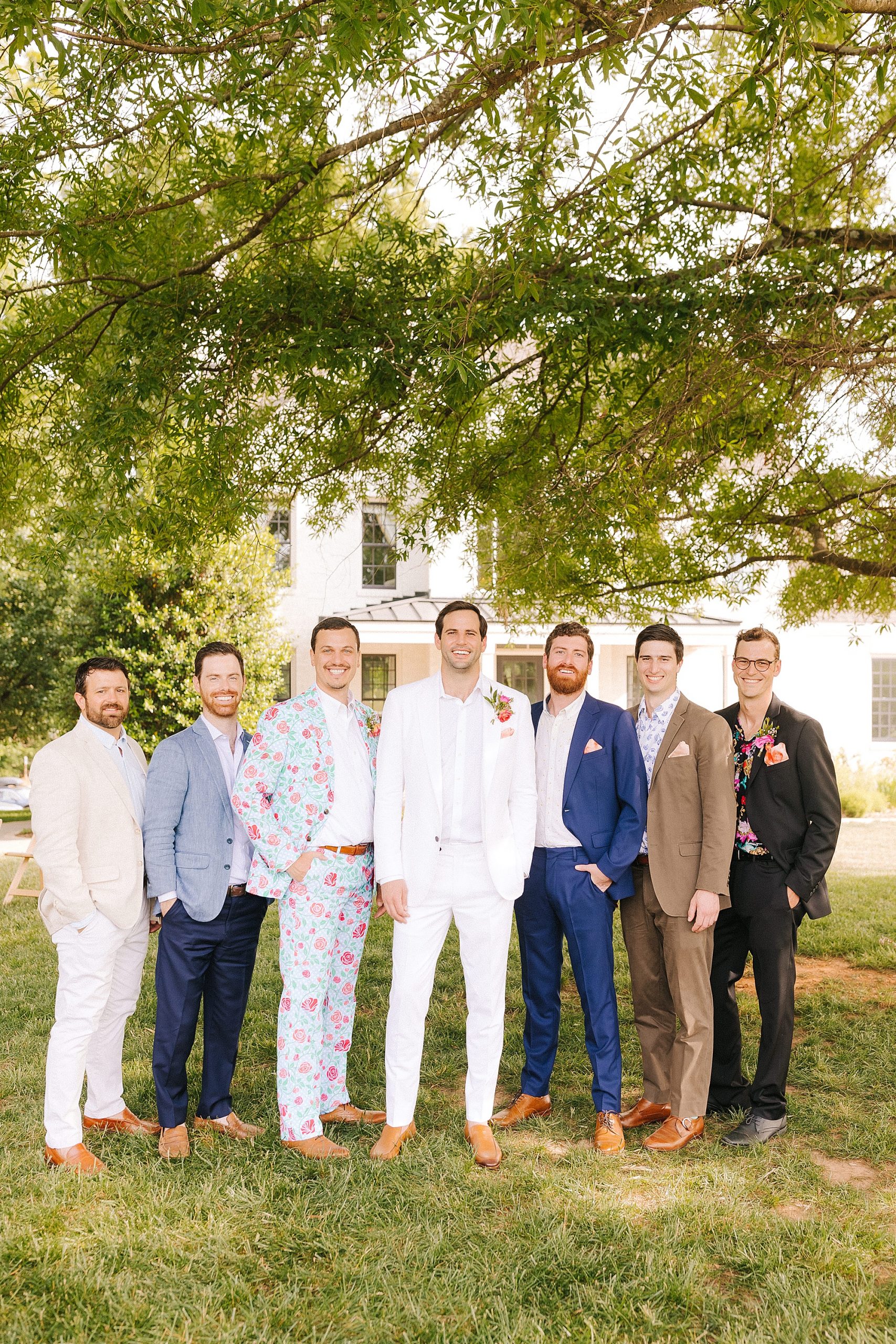 groom poses with groomsmen in mismatched suits