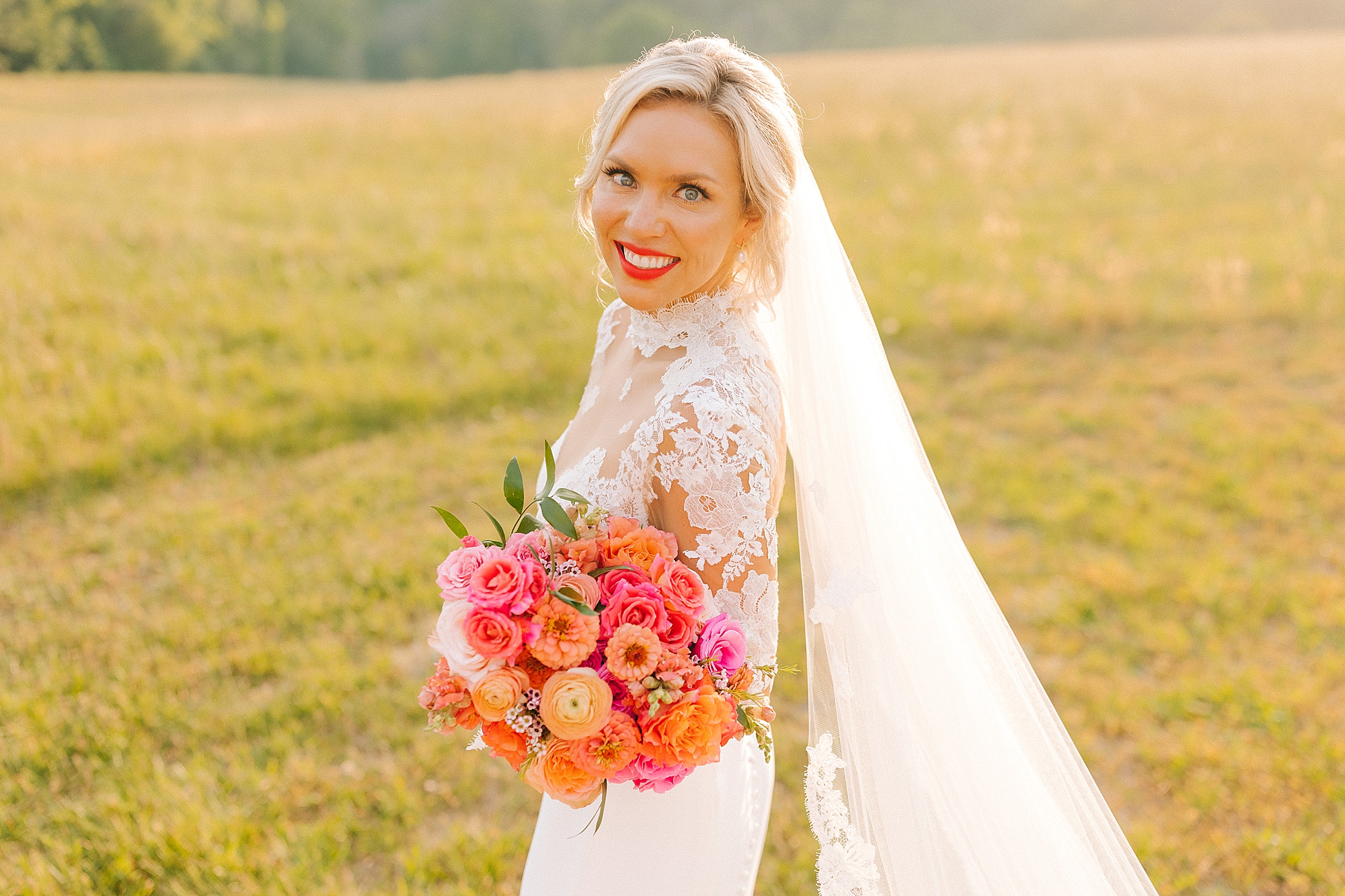 bride holds bouquet of bright pink and orange flowers at The Meadows Raleigh