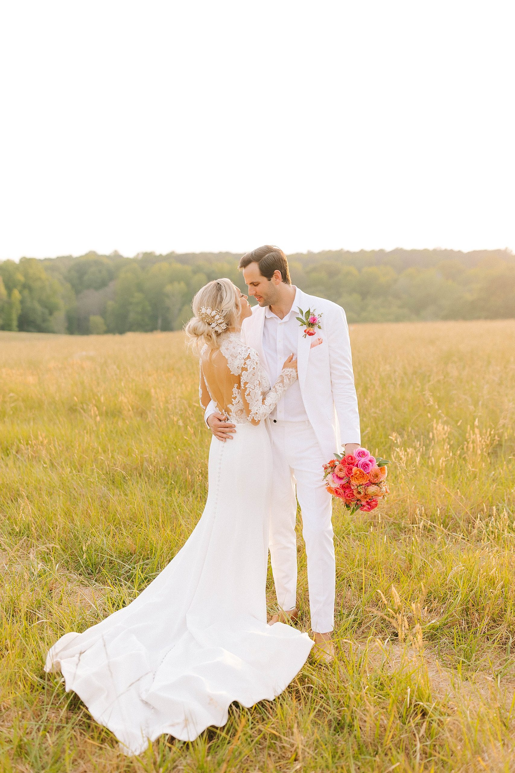 newlyweds stand in field in all white 