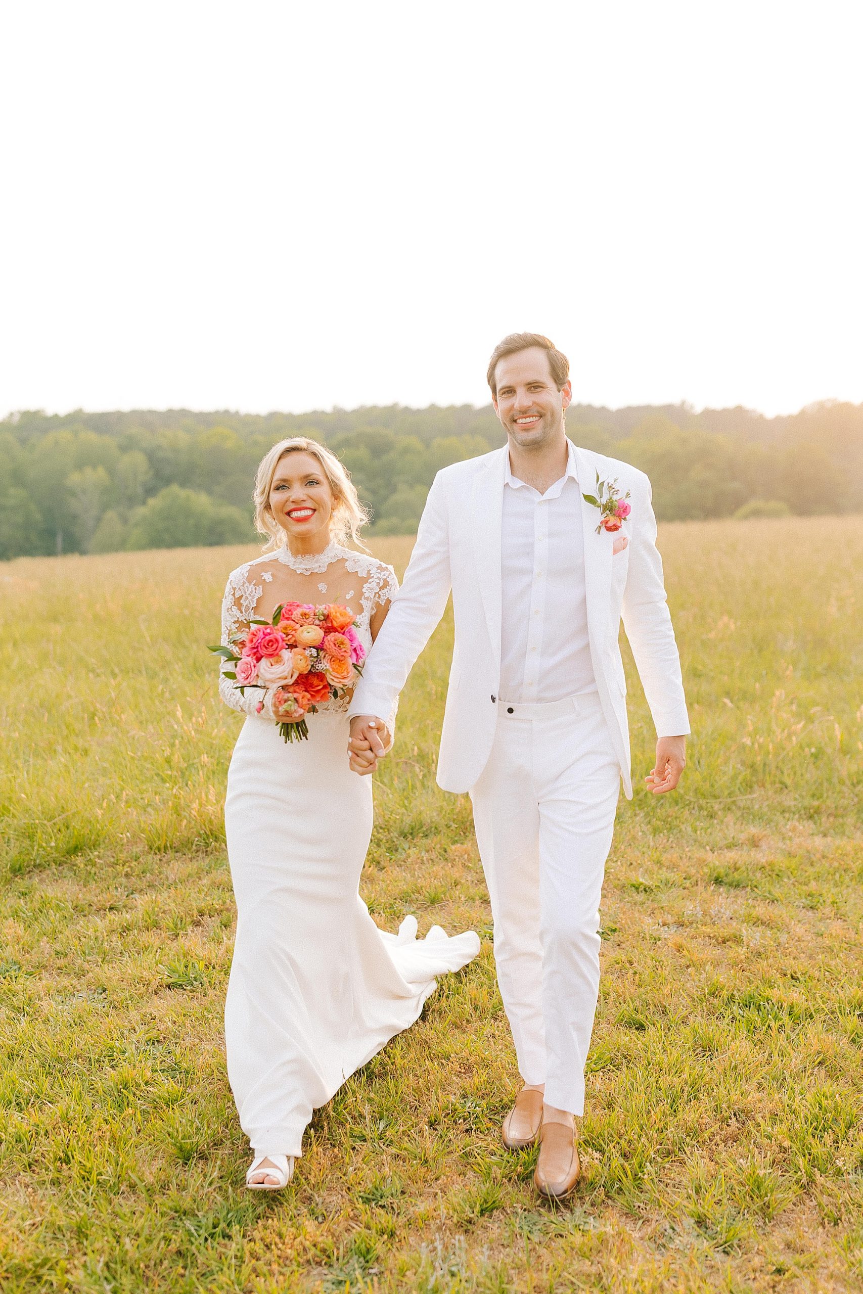newlyweds hold hands and walk through field 