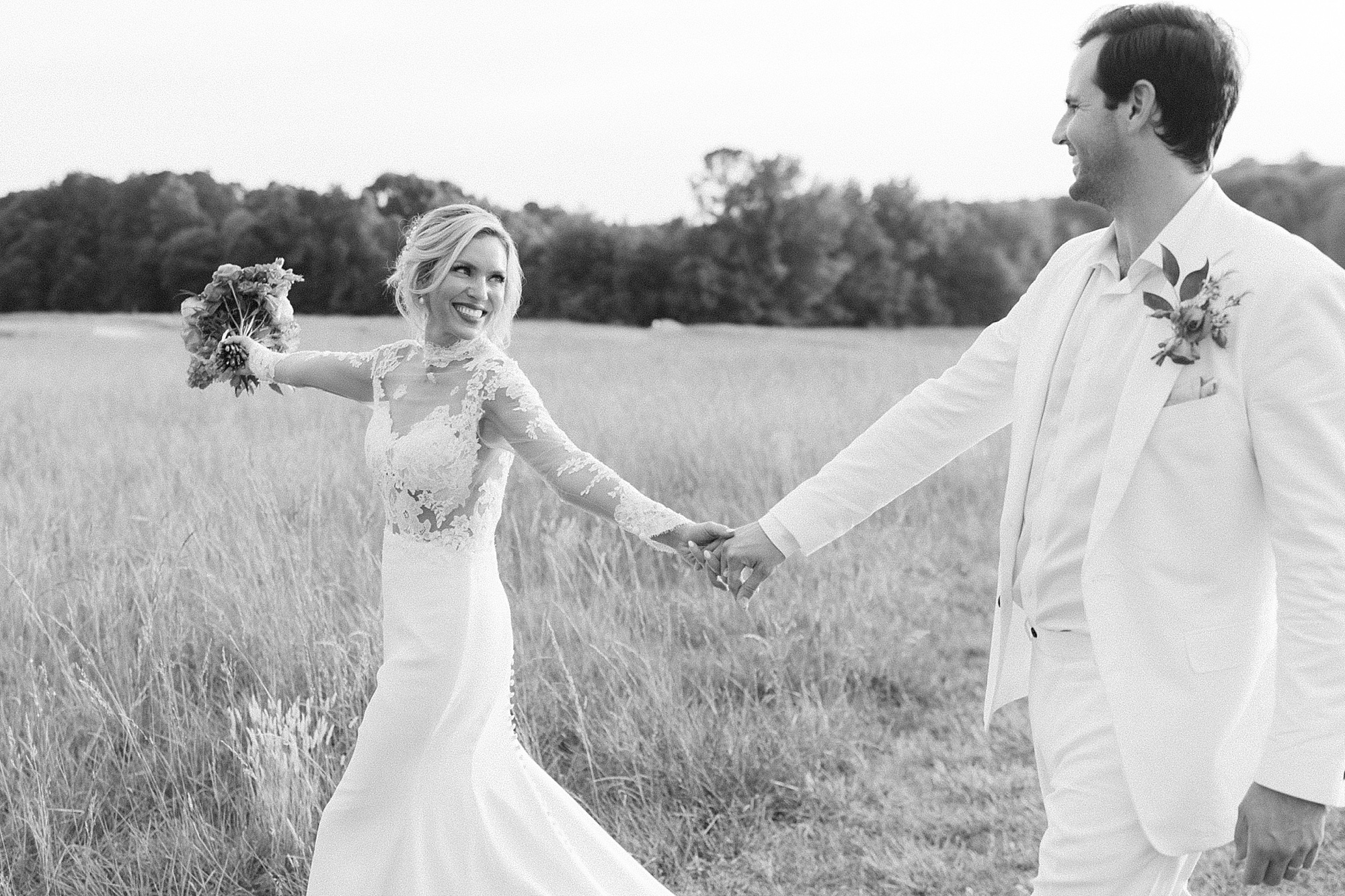 groom holds bride's hand twirling in field