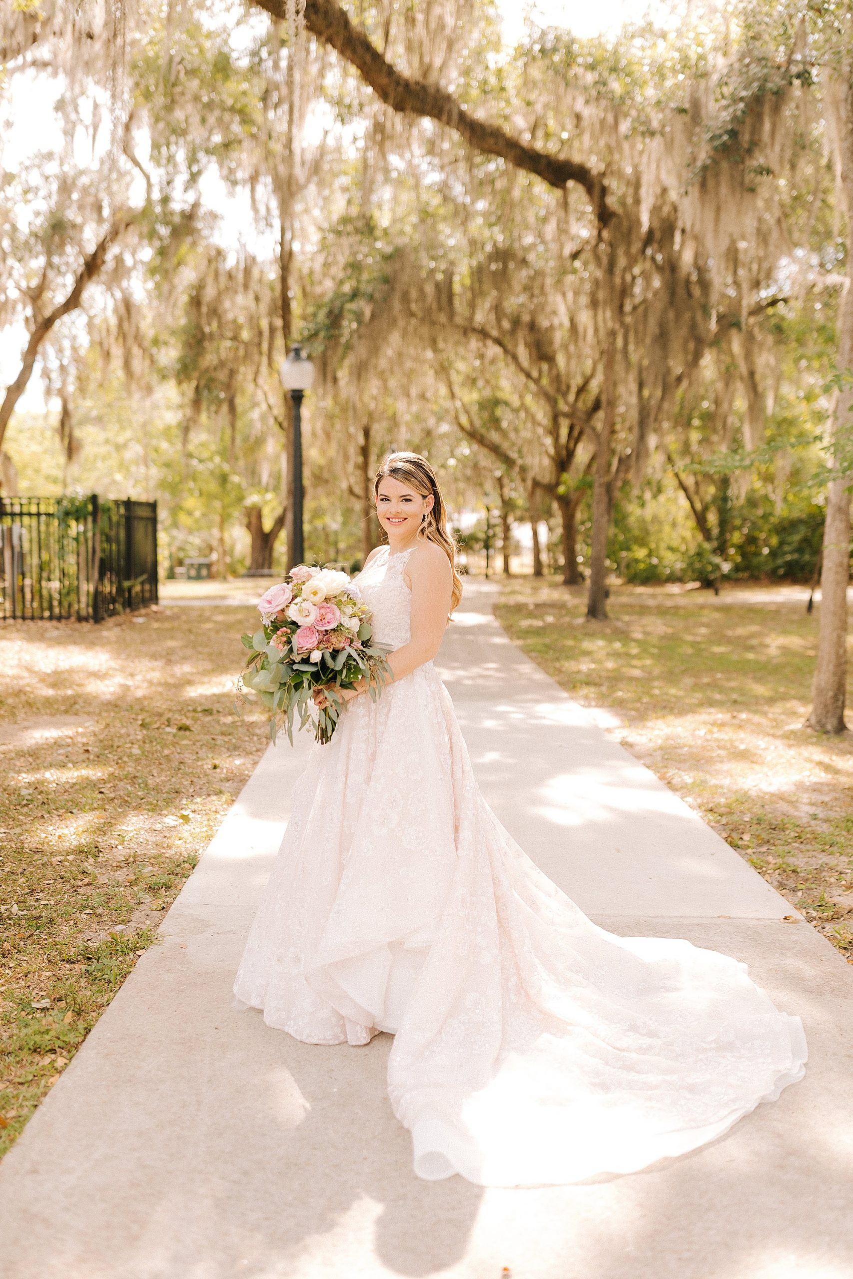 bride poses on sidewalk holding colorful bouquet