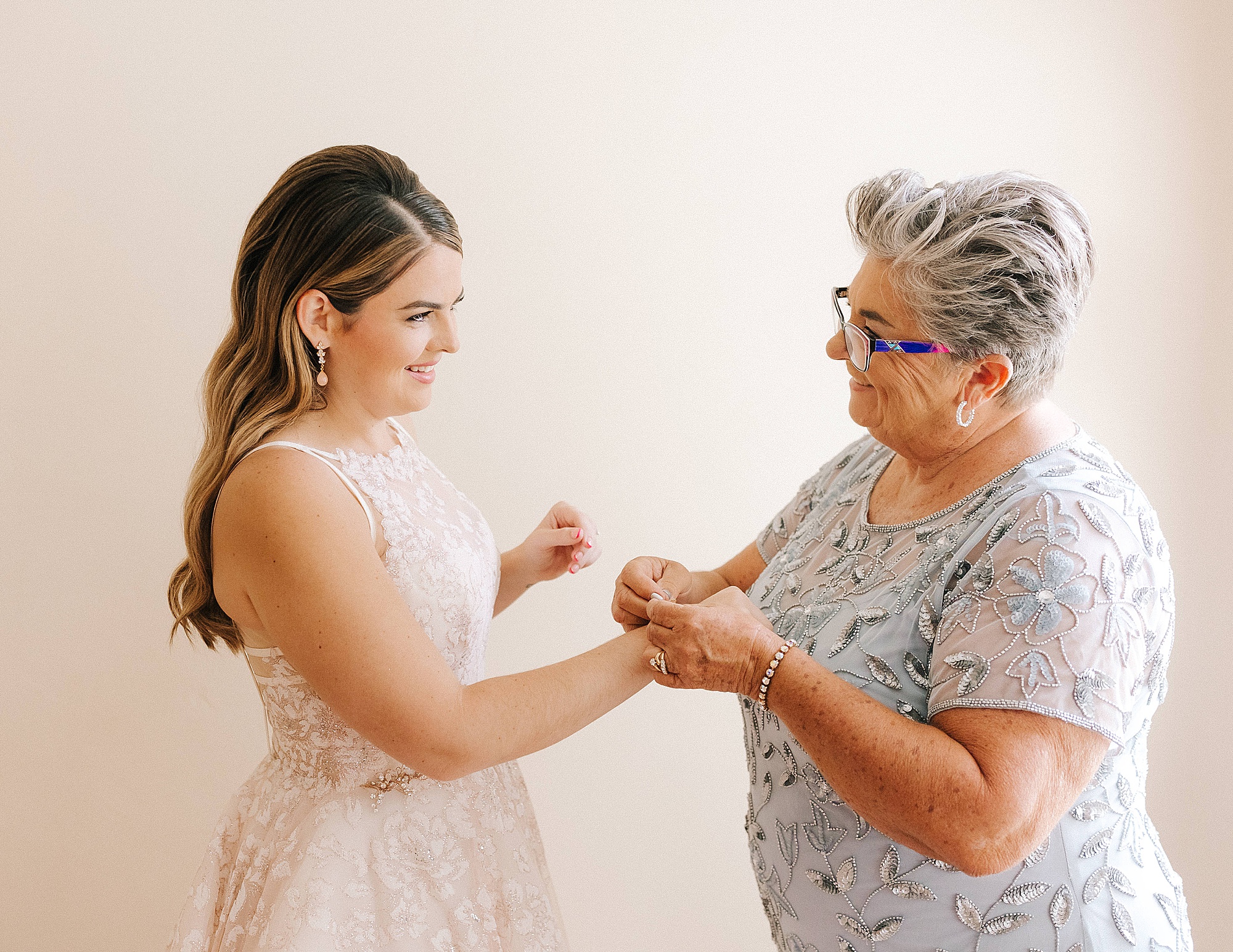 mother helps bride with jewelry on wedding day 