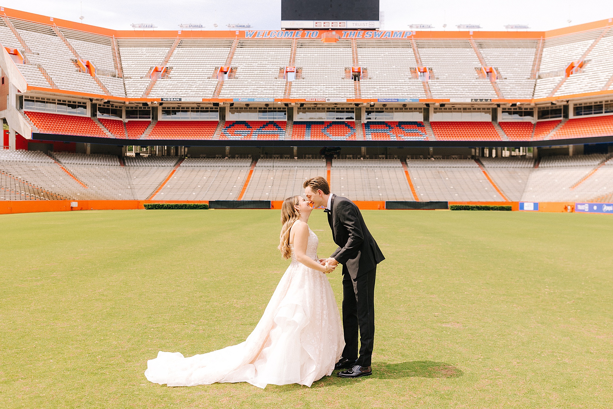 bride and groom kiss on football field at University of Florida