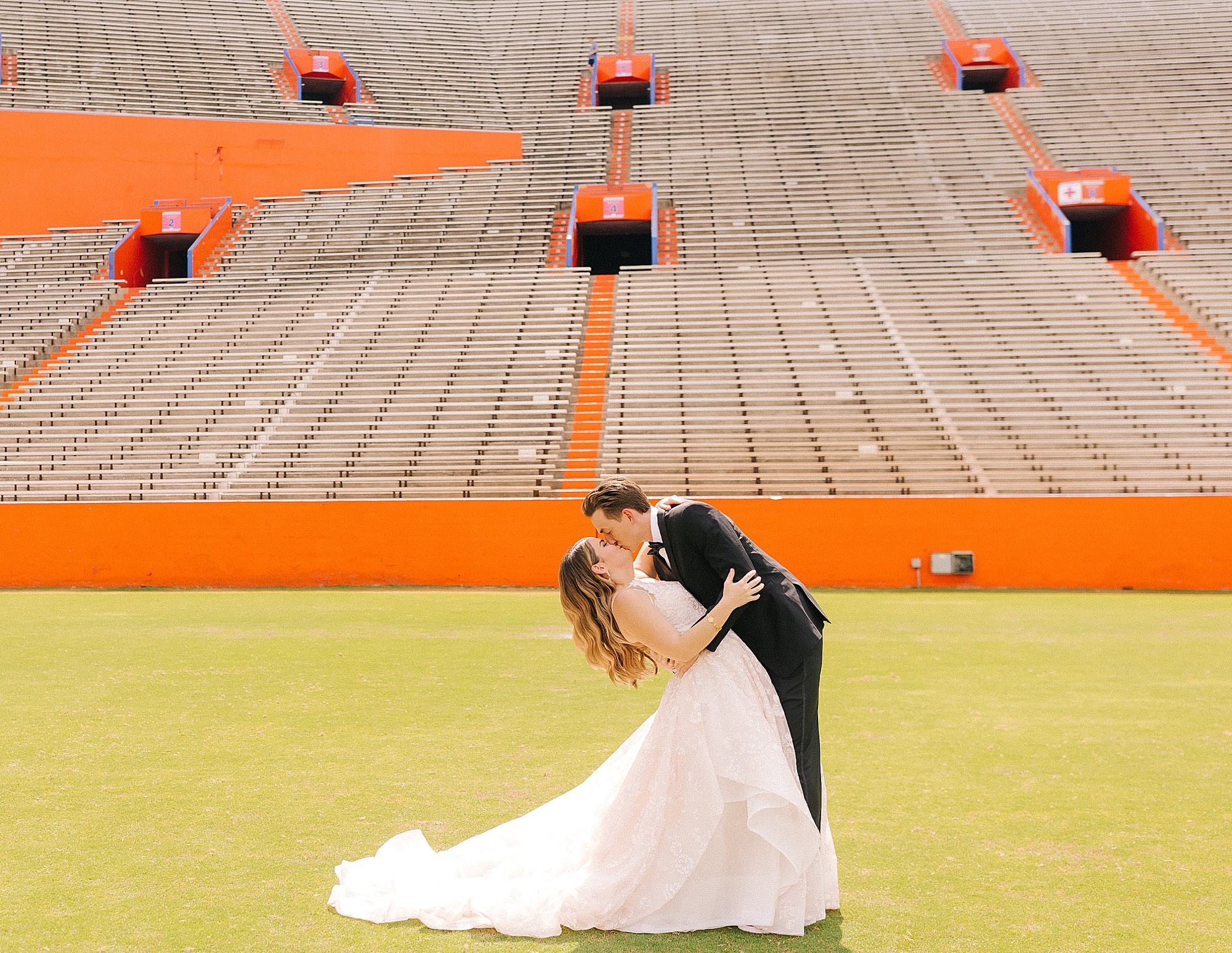 groom kisses bride on University of Florida field