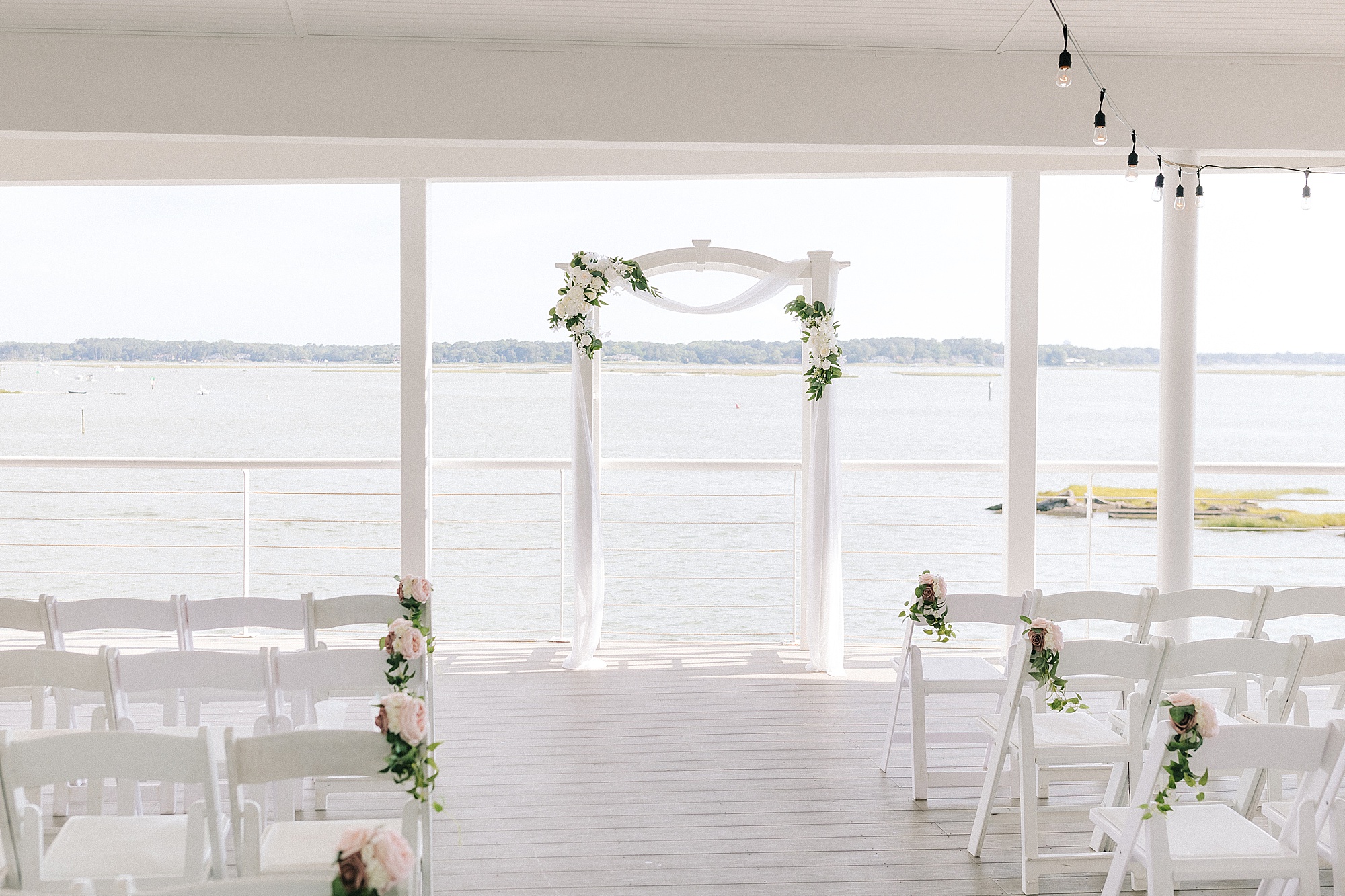 white arbor with greenery for waterfront wedding ceremony in Virginia Beach