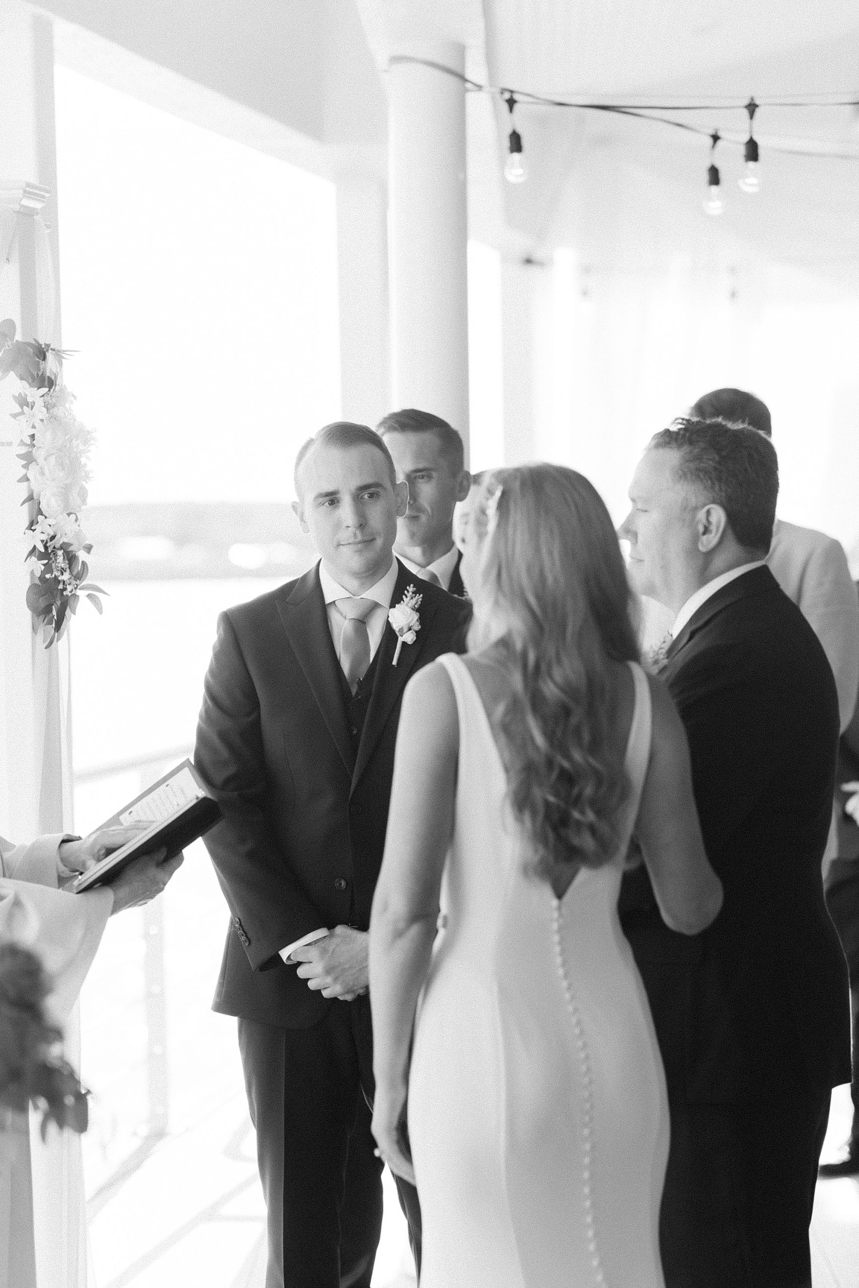 groom looks at bride and father during waterfront wedding ceremony in Virginia Beach
