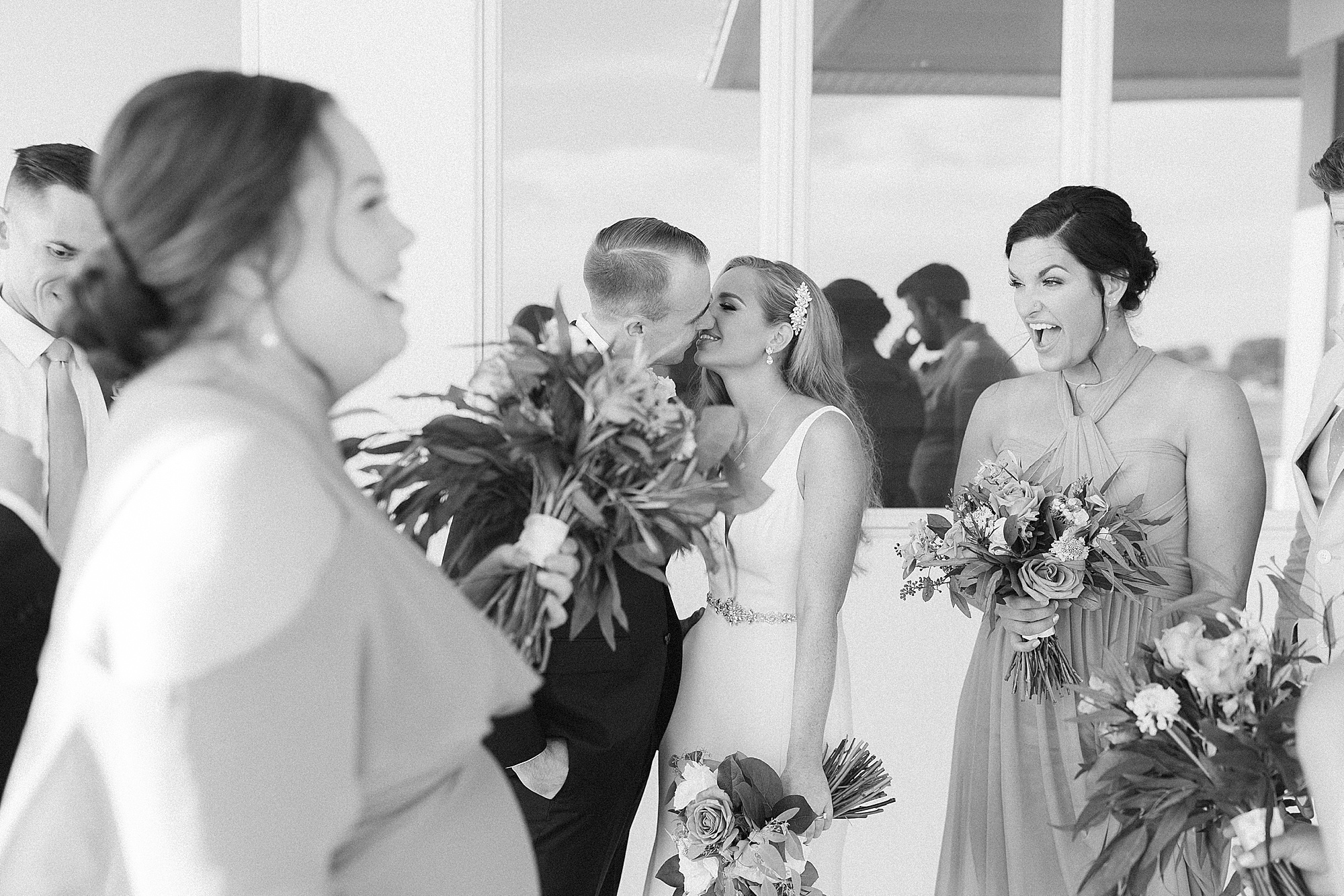 newlyweds kiss while bridal party talks