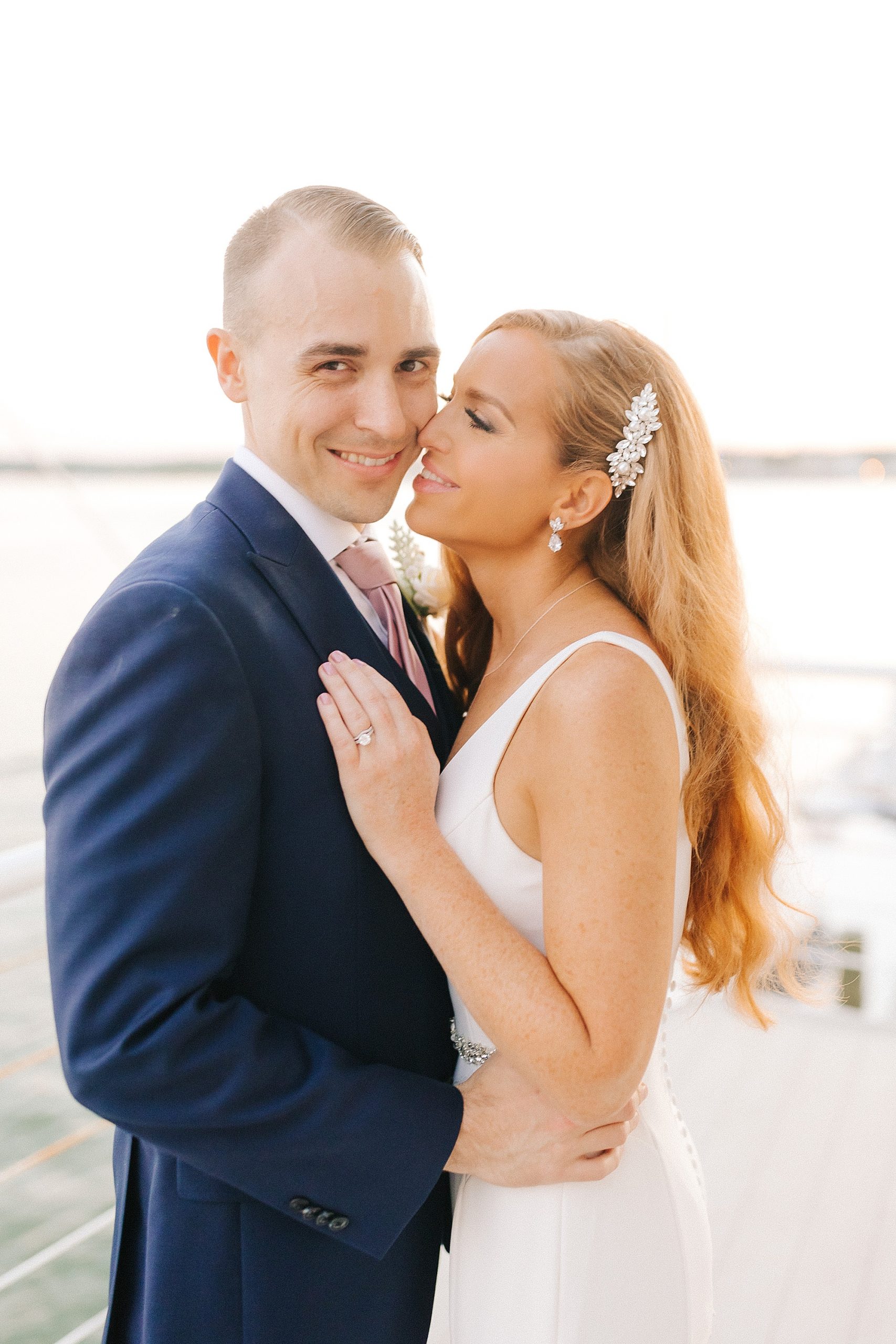 bride kisses groom's jaw during portraits on patio at Lesner Inn