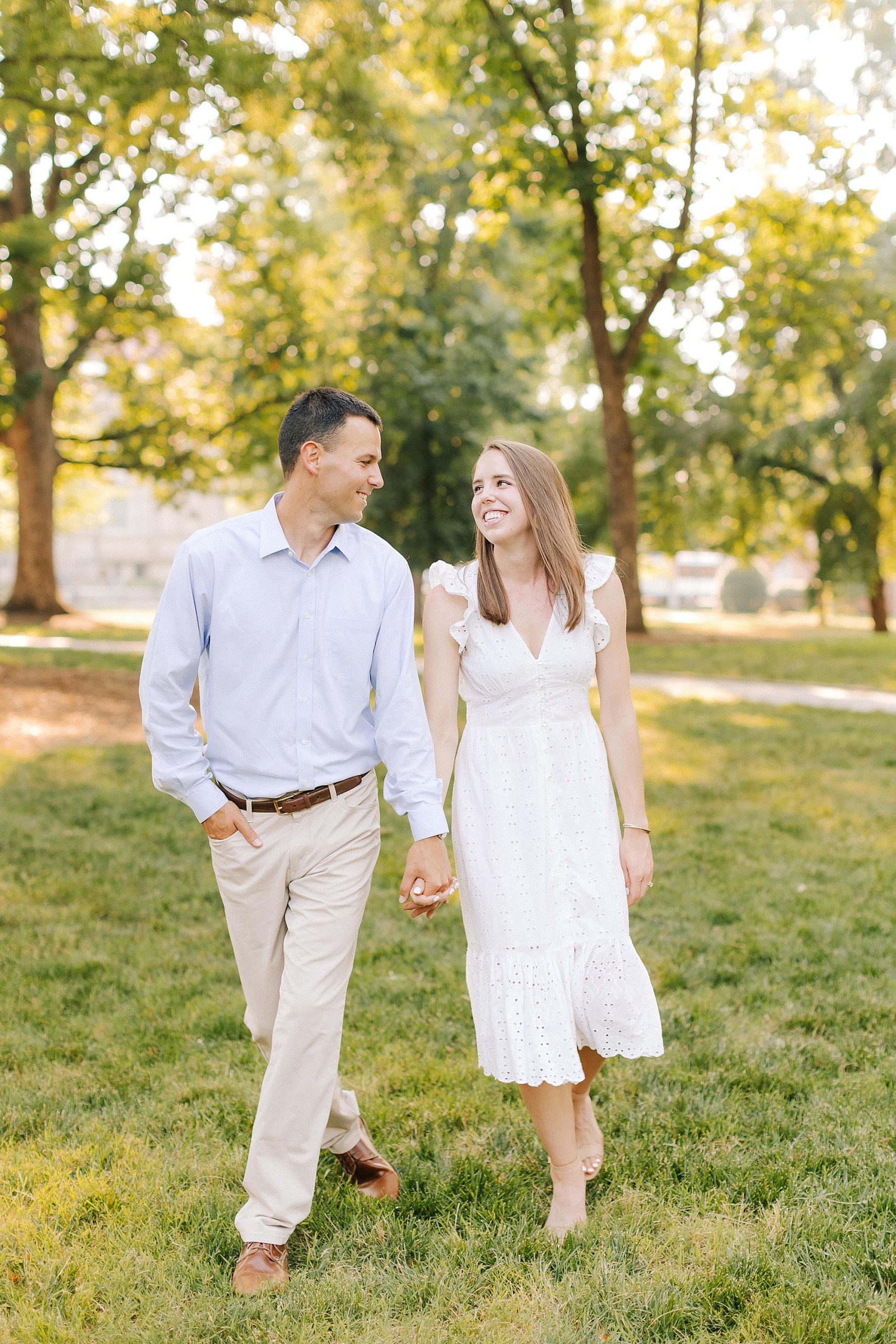 engaged couple walks through grass at UNC Chapel Hill