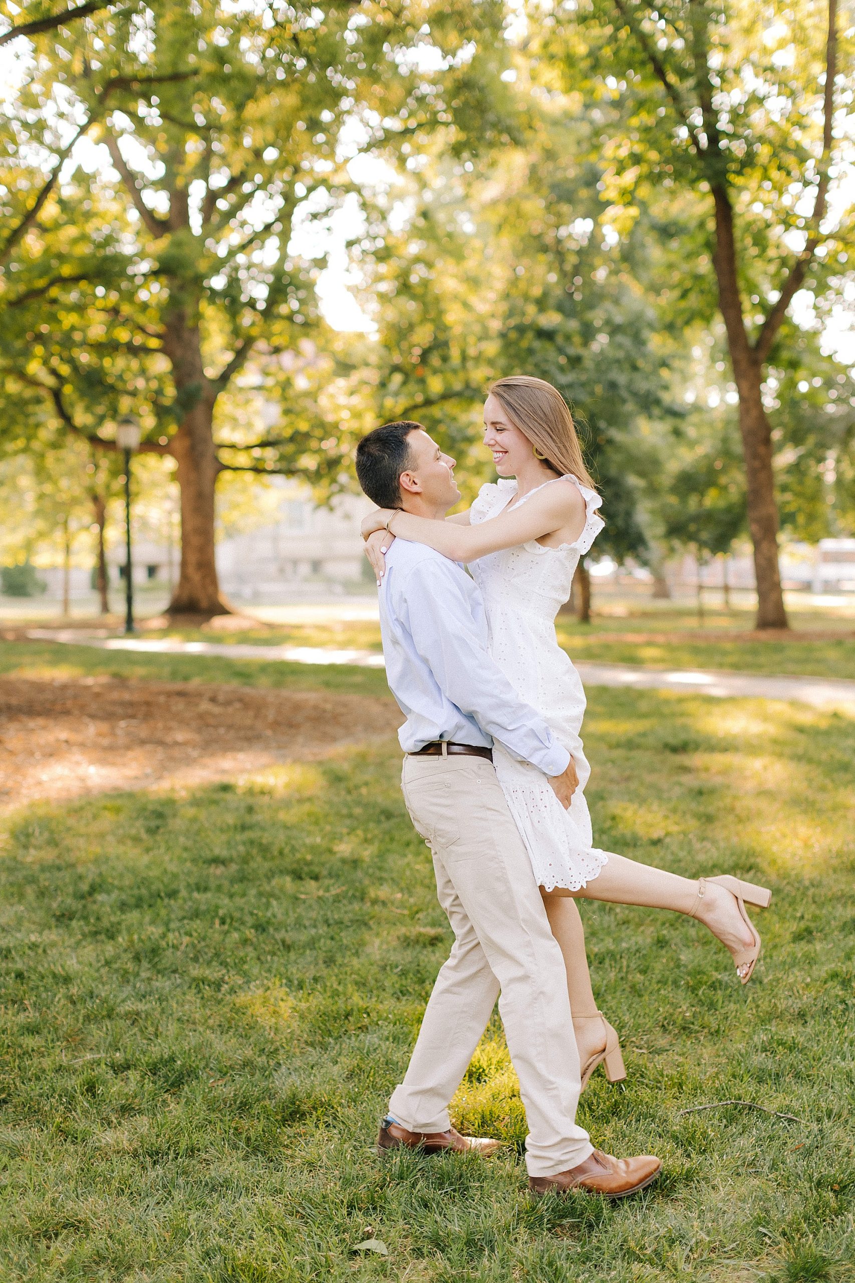 groom lifts bride up during engagement portraits at UNC Chapel Hill