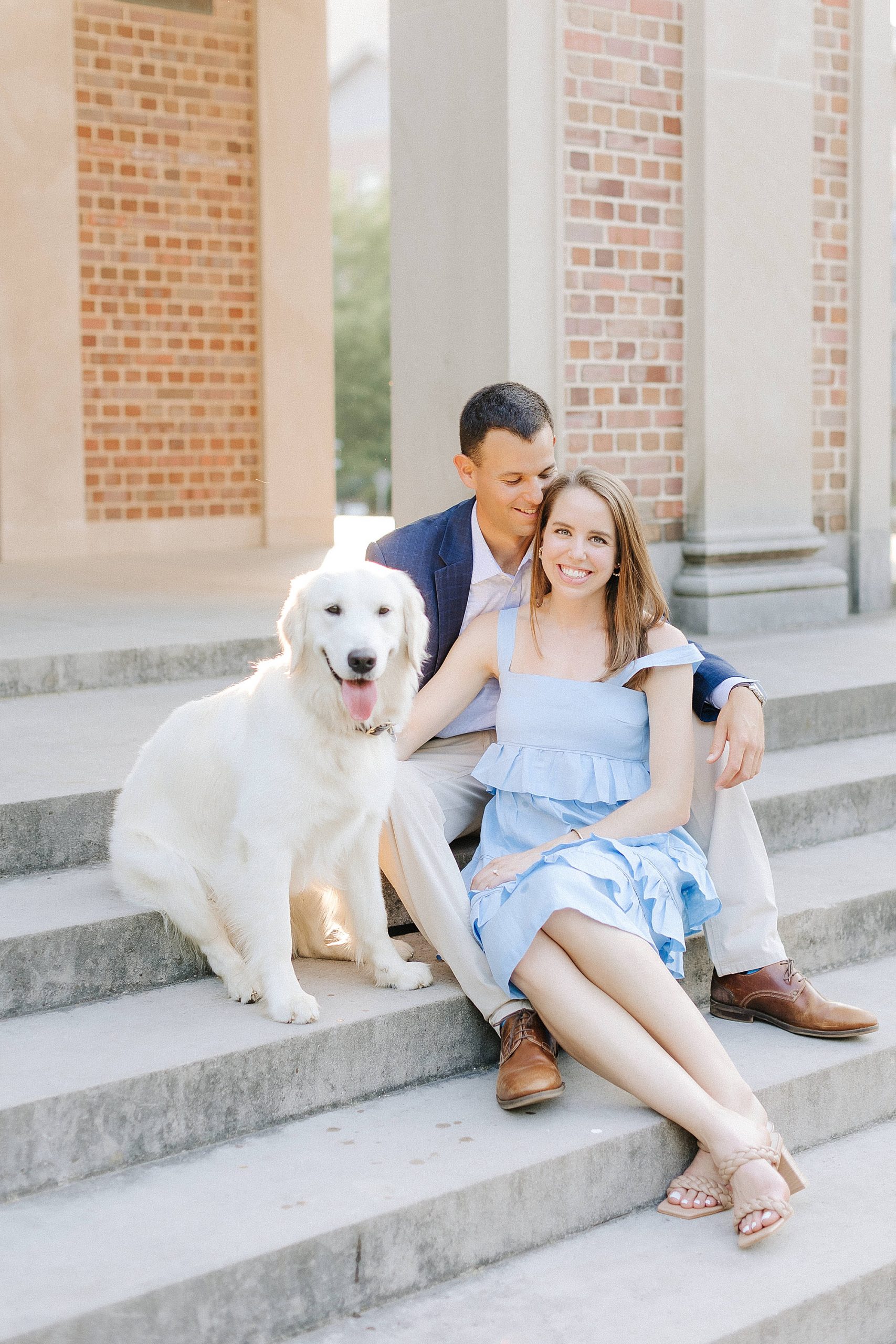 couple sits on steps at UNC Chapel Hill with white dog