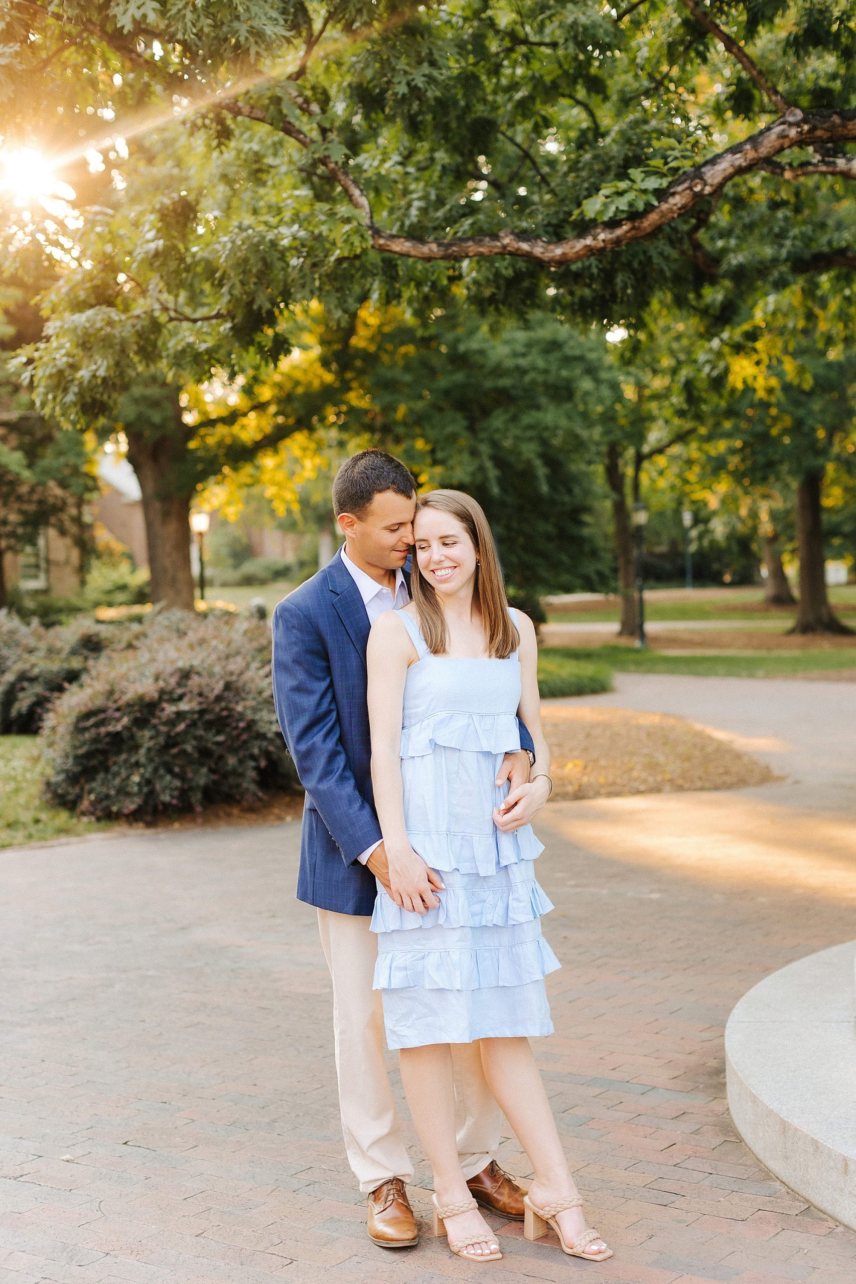 groom hugs bride and holds her hand during UNC Chapel Hill engagement session