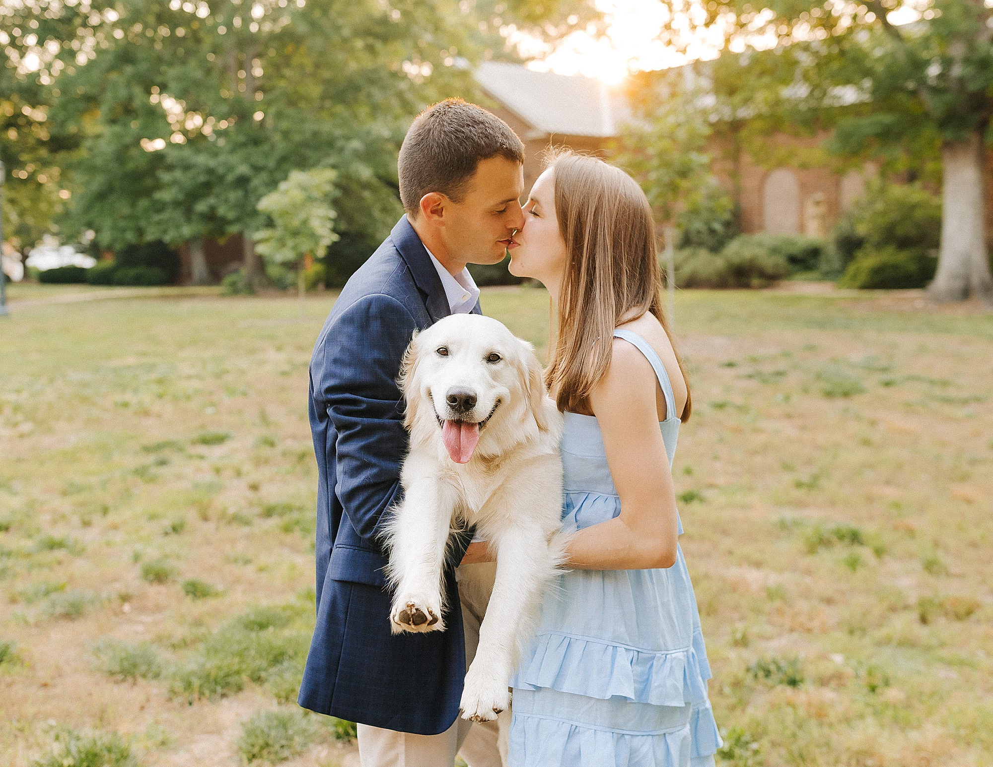couple kisses holding puppy during UNC Chapel Hill Engagement Session