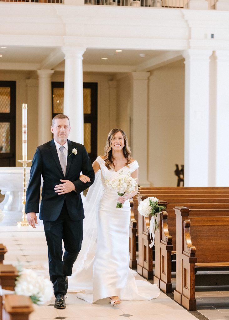 bride walks down aisle during traditional church wedding in Raleigh NC