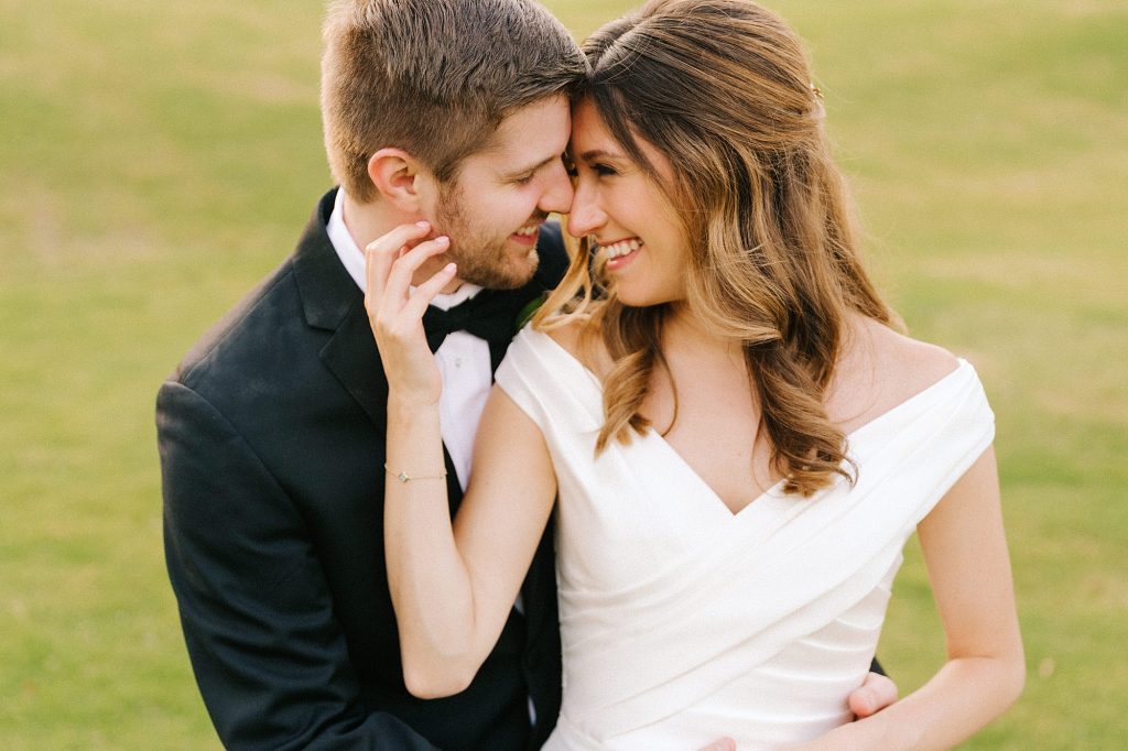 bride holds groom's cheek during NC wedding photos at Prestonwood Country Club