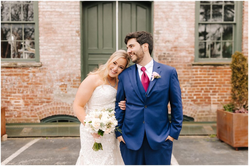 Couple stands in front of their wedding venue, Melrose Knitting Mill in Raleigh, NC