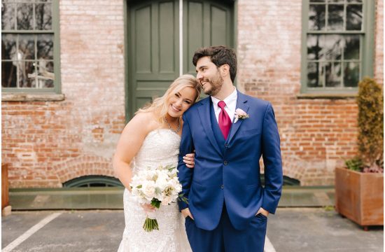 Couple stands in front of their wedding venue, Melrose Knitting Mill in Raleigh, NC