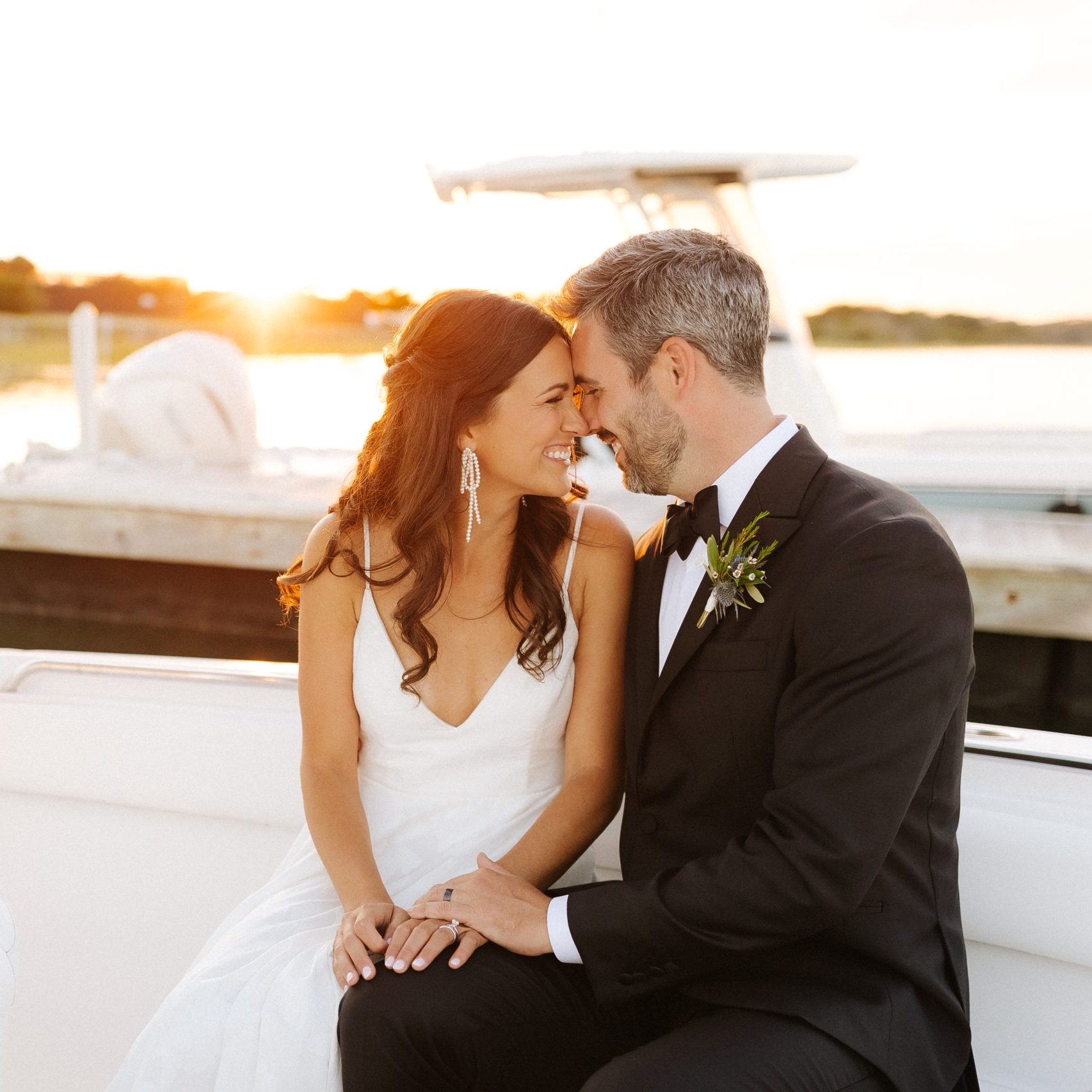 Couple sits on a boat at sunset on their wedding day at Figure Eight Island
