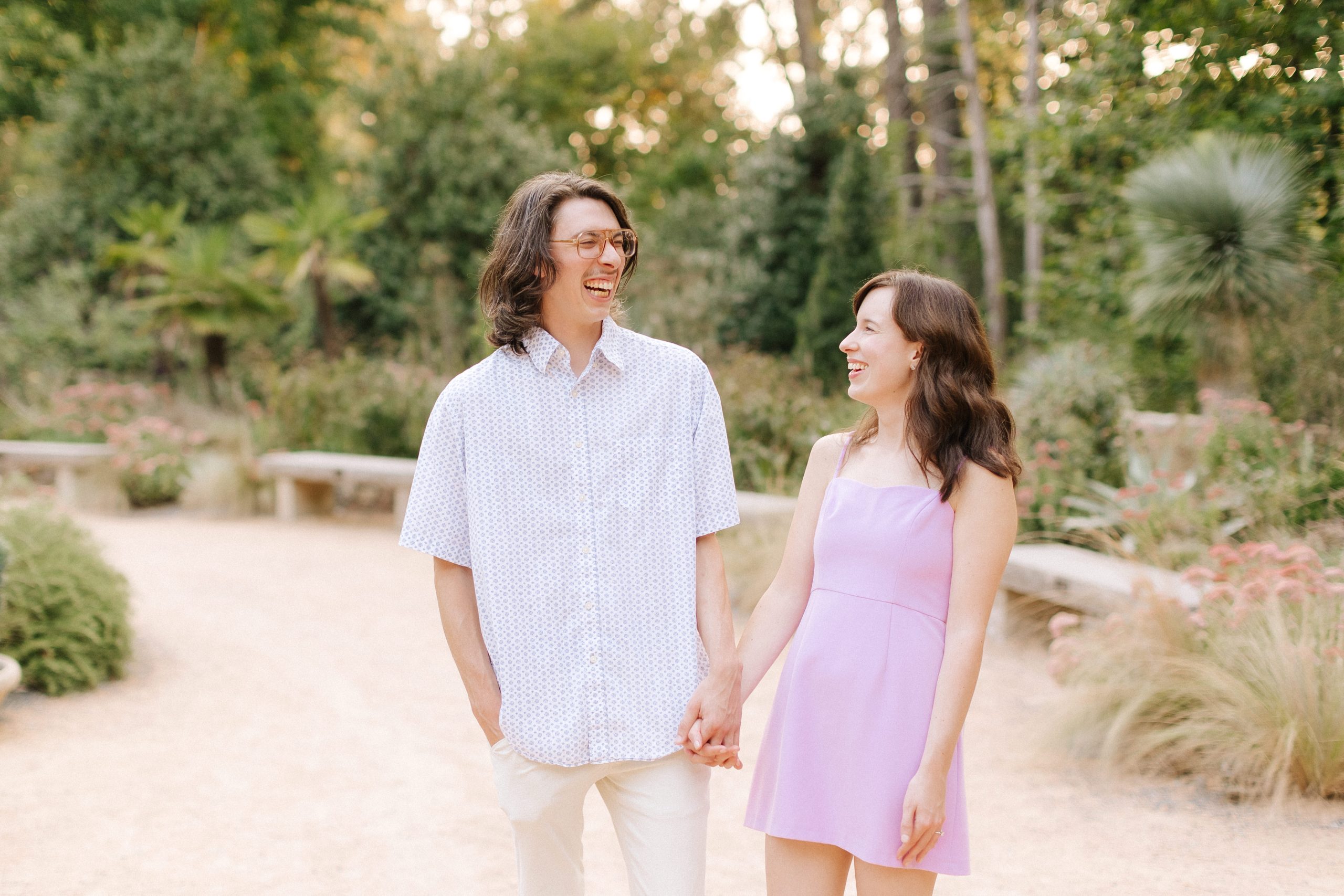 a couple laughs together during their engagement session at Duke Gardens in Durham, NC