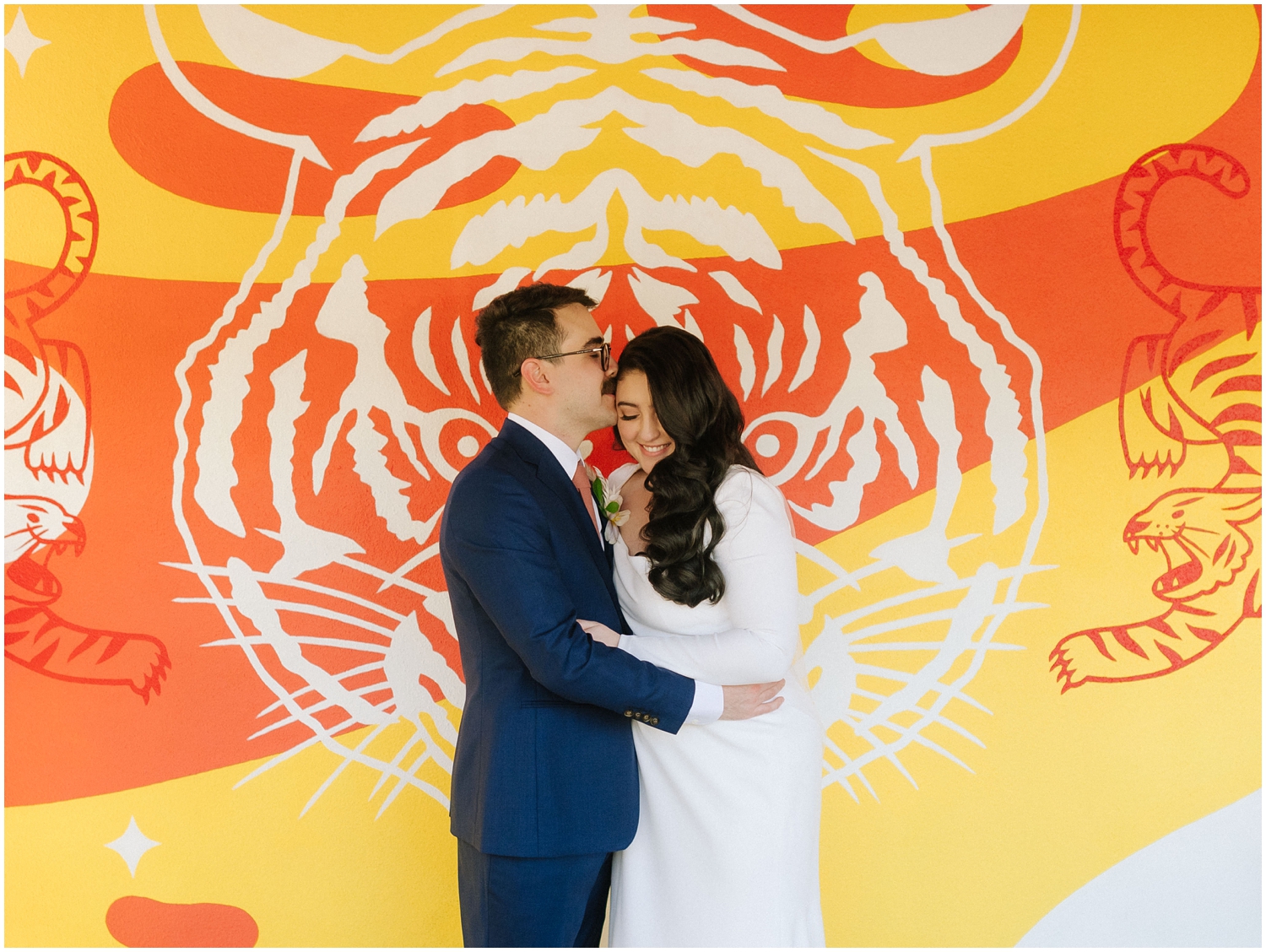 couple holds each other on their wedding day in front of a colorful mural in South Tampa