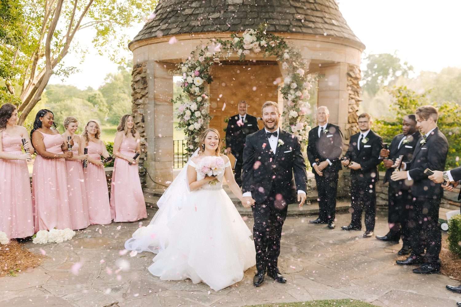 A couple walks through floral confetti after saying I Do at Graylyn Estate in Winston-Salem, NC