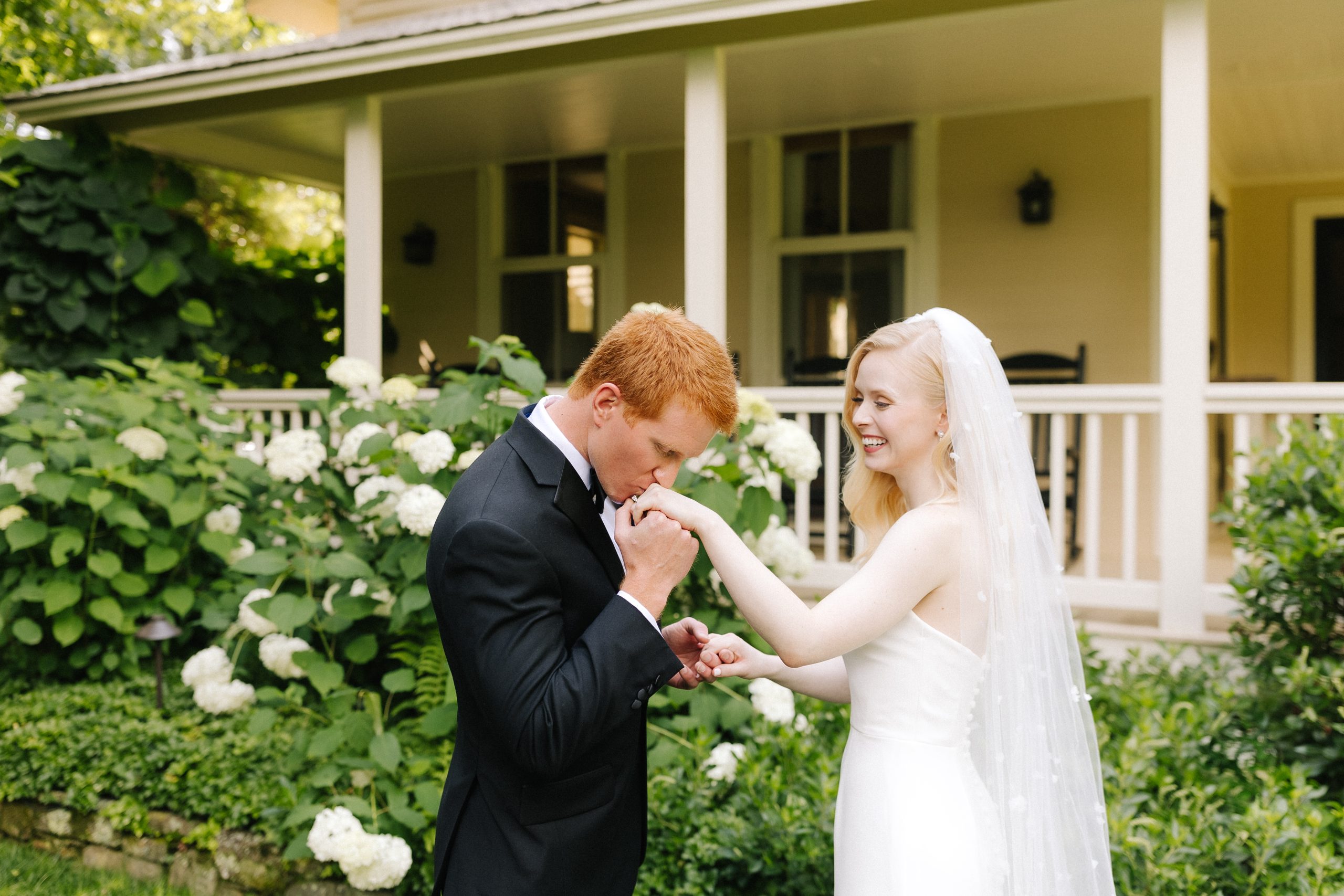 Groom Kisses Bride on the hand during their first look at Old Edwards Inn in Highlands, North Carolina