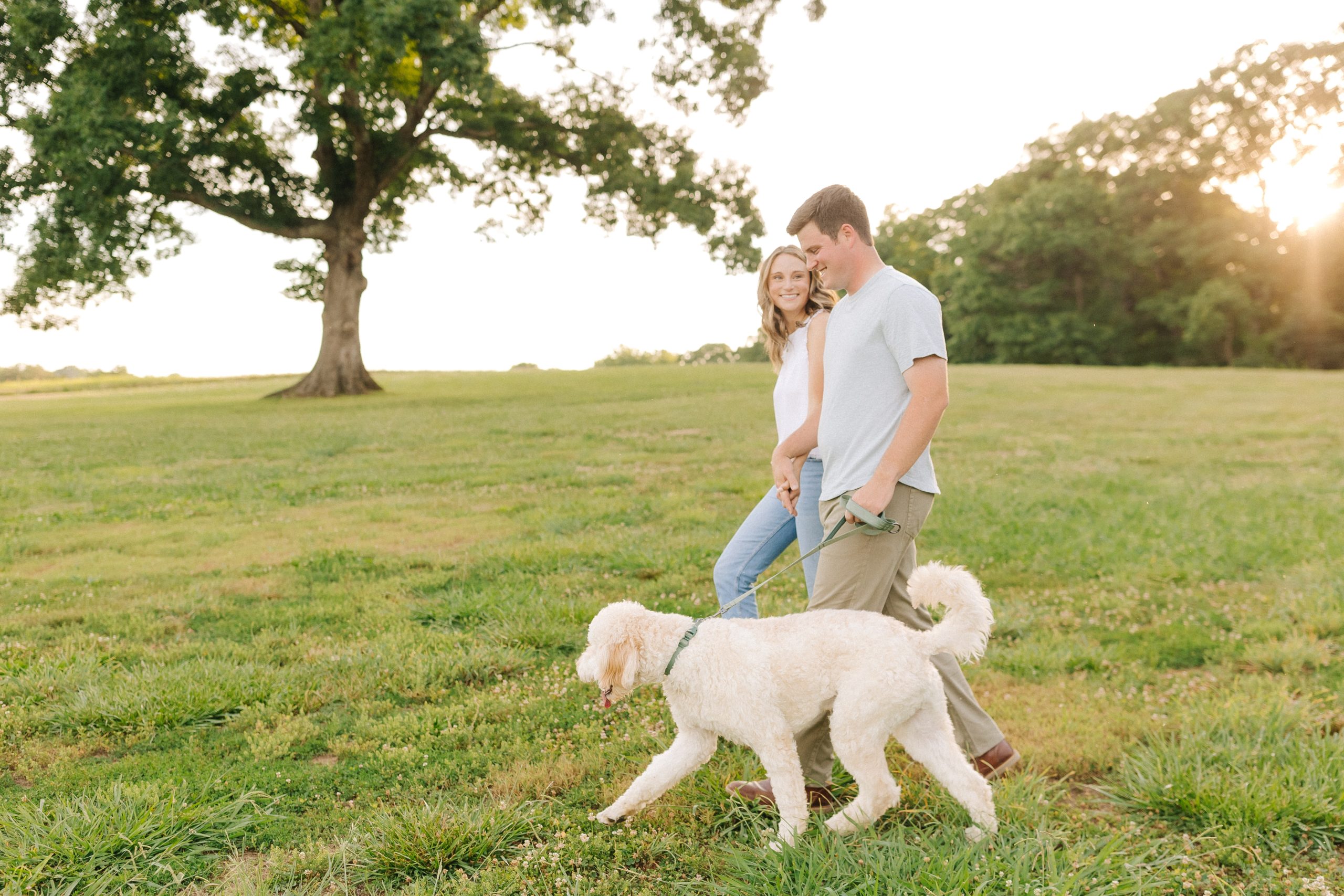 A couple walks with their golden doodle at Summerfield Farms in North Carolina
